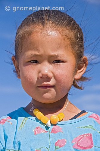 Small Mongolian girl in a blue top and yellow beads.