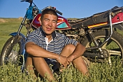 Mongolian man with motorbike in the wide open pasture-land of the Mongolian steppe.