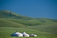 Image of Three yurts on the grassy slopes of the mountains.