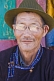 Image of Mongolian carpenter in hat and traditional buttoned jacket.