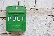 Green post-box on a whitewashed wall.