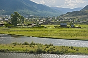 caption: Small Russian town of log houses nestles between the Altai Mountains and the river.