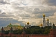 The golden domes and green copper roofs of the Kremlin contrast a cloudy sky.
