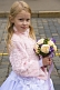 Image of Young blonde Russian girl dressed as a bridesmaid holds a bunch of flowers on Red Square.