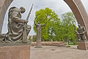 Statues of 2 kneeling soldiers guard the Soviet war memorial with its eternal flame.