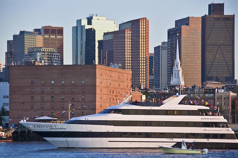 Luxury cruiser 'Odyssey' sails through Boston harbor in late evening.