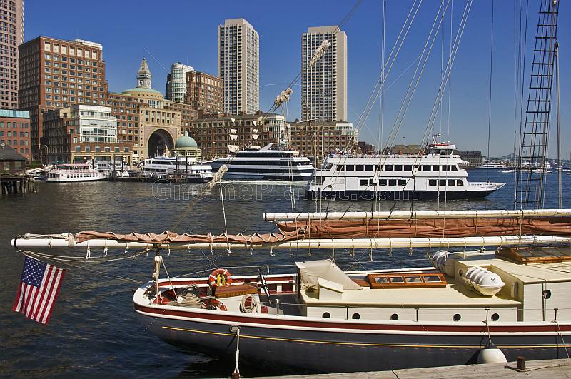 Sail and power boats of many types fill the inner harbor, backed by tall office buildings.