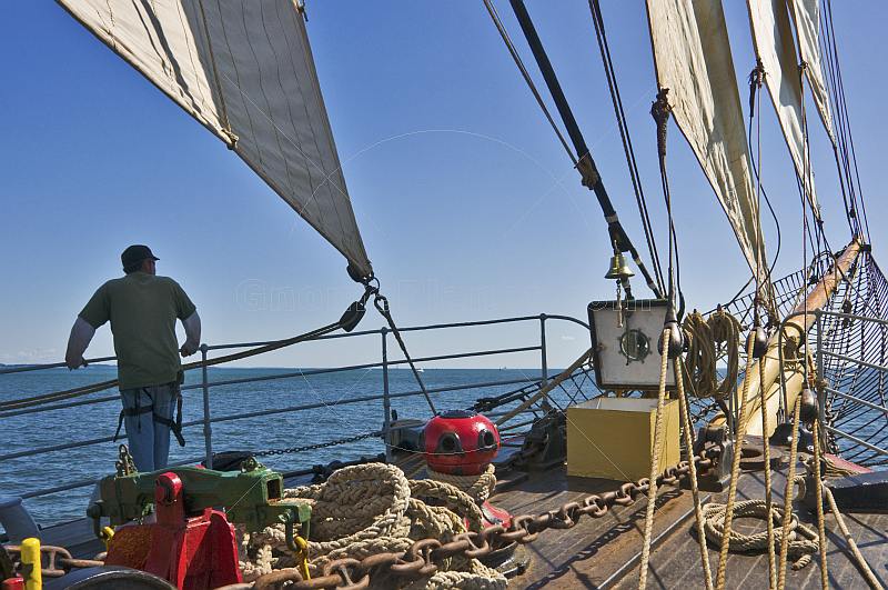 Lookout on watch in the bows of the sailing ship 'Picton Castle' as she cruises along the Massachusetts coast.