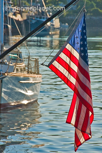 U.S.A. flag 'Stars and Stripes' hangs from boom on sailing ship in harbour.