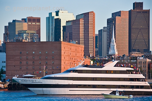 Luxury cruiser 'Odyssey' sails through Boston harbor in late evening.