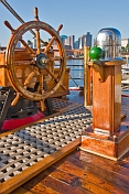 Ships wheel and binacle of the barque 'Picton Castle' against a background of Boston Harbor.