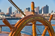 Ships wheel of the barque 'Picton Castle' against a background of Boston Harbor.