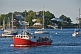 Image of A lobster boat passes moored sailboats as it returns to harbor in the early morning.