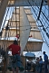 Image of Crew stand on deck of the barque 'Picton Castle' under full sail leaving Boston harbor.