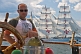 Image of Man at the wheel of the 3 masted barque 'Picton Castle' with tallship 'Sagres' in background.