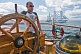 Image of Man at the wheel of the 3 masted barque 'Picton Castle' with tallship 'Sagres' in background.