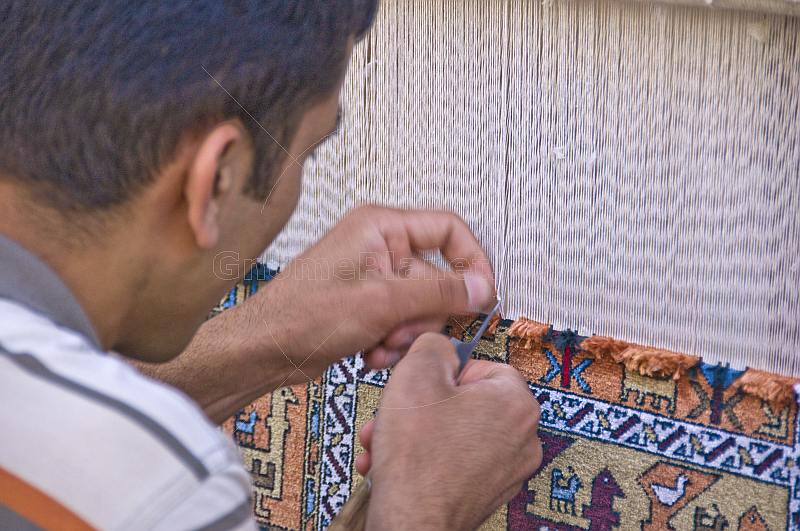 Uzbek carpet weaver knots another thread to his silk rug.