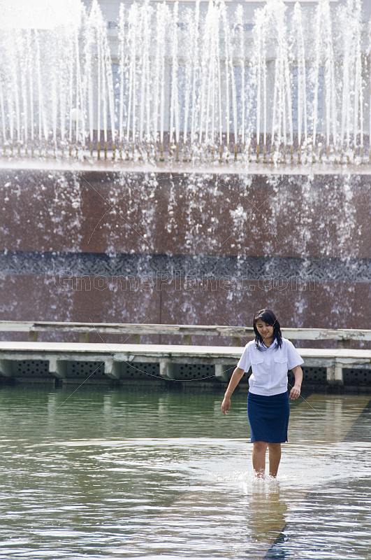 Office worker girl walking through Fountain near the Oliy Majlis Parliament.