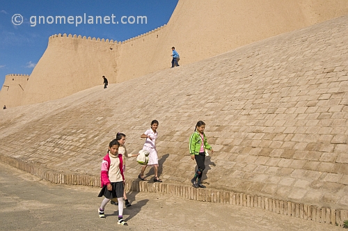 Schoolgirls walk in front of the city walls.