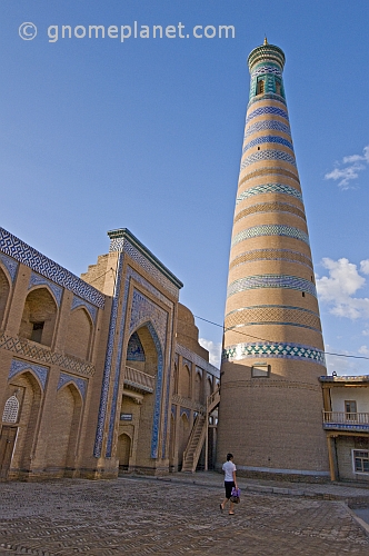 A young girl walks to work past the minaret and madrassah of Islam-Khodja.