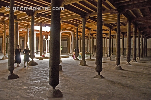 Two young girls stand next to the wooden columns in the Djuma Mosque.