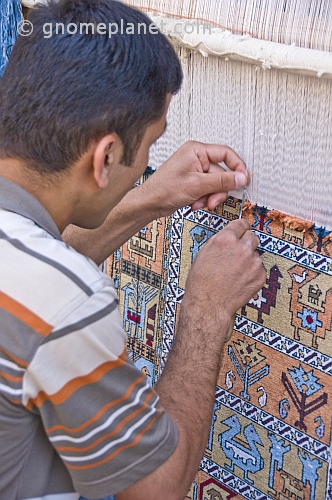 Uzbek carpet weaver knots another thread to his silk rug.