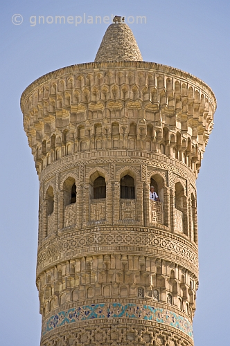 Tourist in white shirt looks out of a window of the Kalon Minaret.