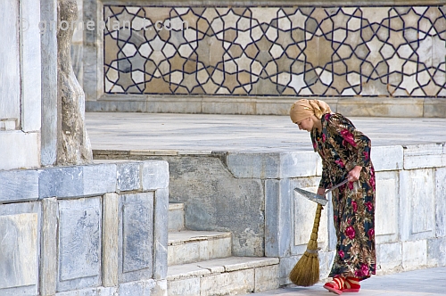 A lady sweeper cleans the marble floor in front of the Ulugbek Medressa.