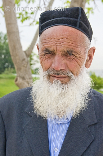 Local elderly Uzbek man with white beard and traditional hat.