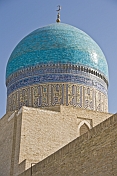Sunshine reflects off the luminous blue tilework on a dome of the Miri-Arab Madrassah.