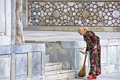 A lady sweeper cleans the marble floor in front of the Ulugbek Medressa.