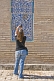 Image of Tourist woman photographs some blue glazed ceramic tilework on the Mohammed Amin Khan Medressa.