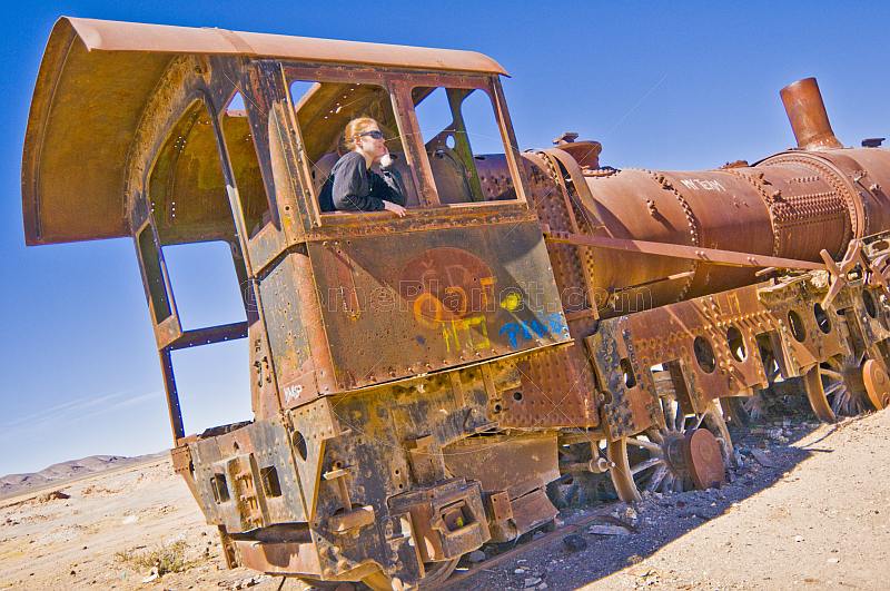 Woman in cab of rusting steam locomotives in the cemetery of steam engines.