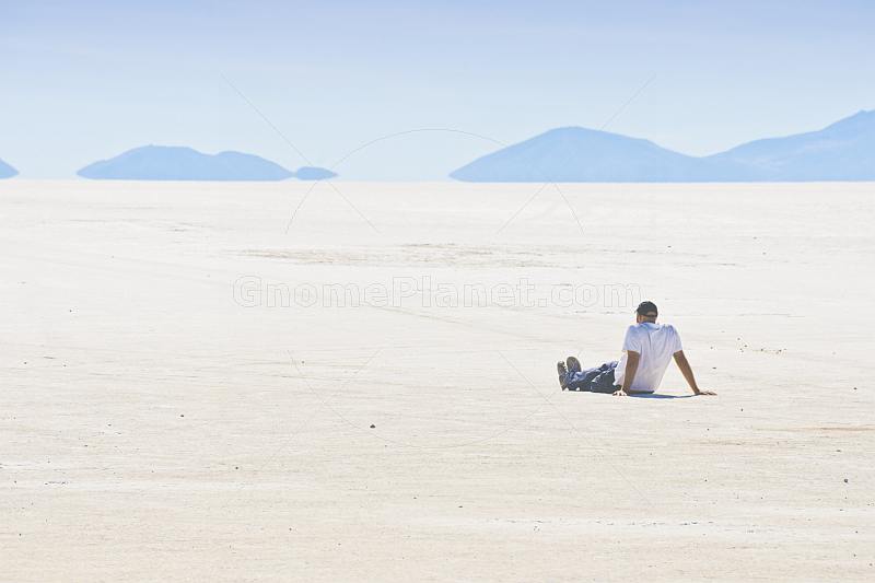 Man sits on the Uyuni Salt Flats to admire the view.