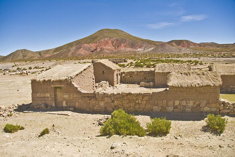 Stone and adobe homestead in a dry and dusty valley.