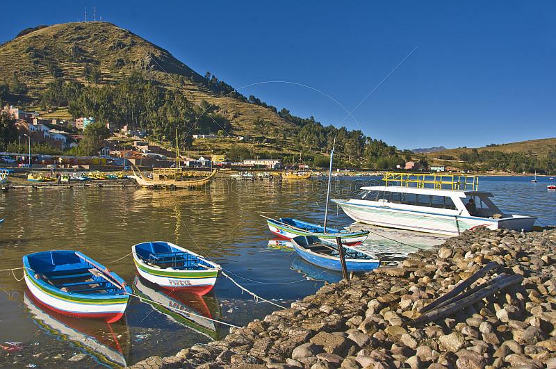Boats moored on the breakwater and a view of the shore of Lake Titicaca.