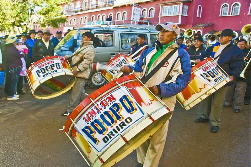 Drummers lead a brass band through the streets in a traditional town festival.