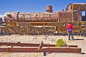 Woman looks at rusting steam locomotive in the cemetery of steam engines.