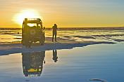 Man with Land Rover viewing the sunset on the Uyuni Salt Flats.