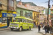 A bus climbs a steep street covered with many electric cables.
