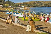 Locals look at a jumble of pedalos pulled up on the beach of Lake Titicaca.