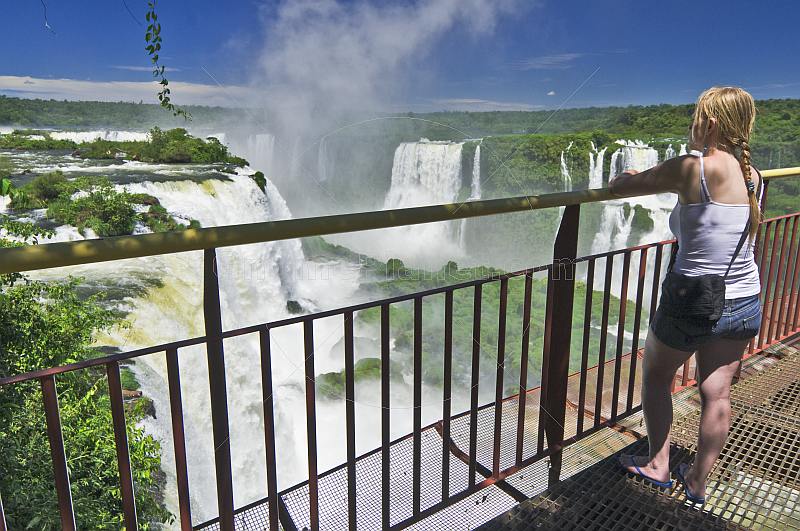 A female traveller views the waterfalls cascading into the Iguazu River.