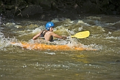 Canoeist in orange kayak negotiates rapids.