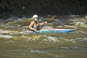 Young canoeist in black kayak negotiates the rapids.