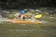 Image of Canoeist in orange kayak negotiates rapids.