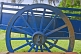 Blue wooden farm cart with mud on the wheel.