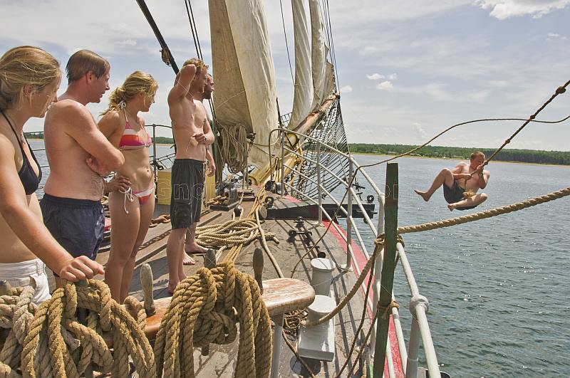 Crew of the 'Picton Castle' wait their turn to swing on a rope and swim in the ocean.