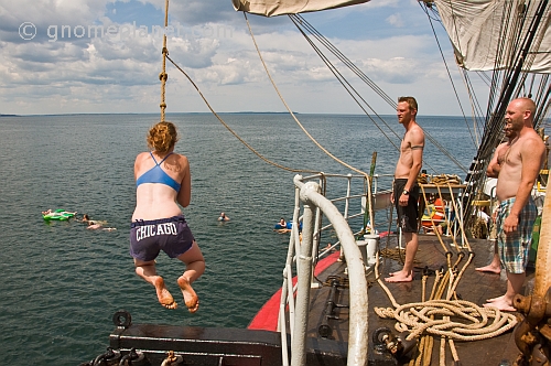Crew of the \\'Picton Castle\\' wait their turn to swing on a rope and swim in the ocean.