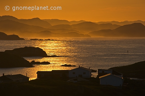 Early morning sun lights the fishing village and distant islands across the ocean inlet.