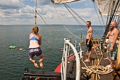 Crew of the \\\\'Picton Castle\\\\' wait their turn to swing on a rope and swim in the ocean.